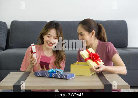 Deux femmes asiatiques aiment ouvrir une boîte cadeau reçue pour une occasion spéciale. Banque D'Images