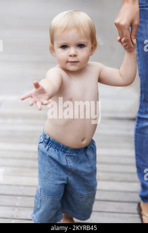 Marcher avec maman. Portrait d'un bébé garçon mignon marchant avec sa mère. Banque D'Images