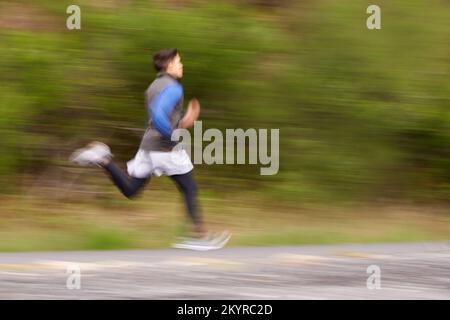 Brûler la route. Image floue d'un jeune homme qui court le long de la route. Banque D'Images