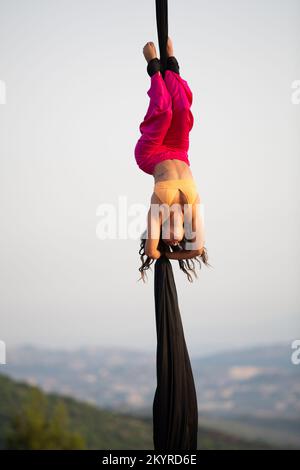 Jeune femme aerialiste qui se produit en soie à l'extérieur Banque D'Images