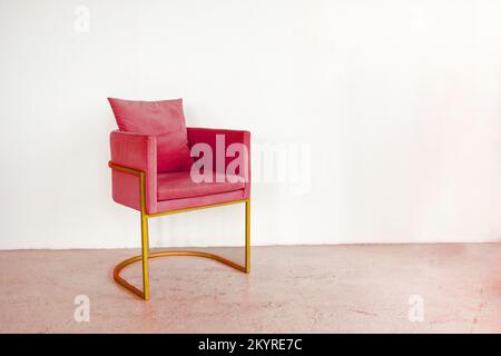 La chaise de créateur tendance se tient contre un mur vide. Fauteuil tonifiant en couleur Viva Magenta. Design créatif tendance de 2023. Photo de haute qualité Banque D'Images