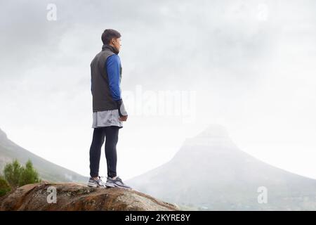 Saluez une magnifique journée d'hiver. Un jeune coureur se tenant au sommet d'une montagne en admirant la vue. Banque D'Images