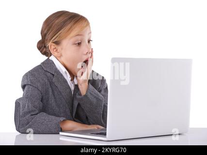 Je n'y crois pas. Adorable jeune fille assise à un bureau surpris de ce qu'elle voit. Banque D'Images