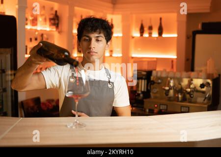 Le barman verse du vin rouge en verre sur un comptoir en bois. Copier l'espace Banque D'Images