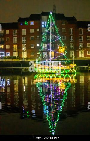 Lumières de Noël en mer. Une brillante parade de bateaux de vacances à Preston, Lancashire décembre 2022. Yachta et voiliers amarrés décorés de lumières de Noël étincelantes à Preston Marinaa. Une soirée de Noël s'allume pour les foules qui bordent le mur du quai tandis que les porte-couchettes illuminent leurs bateaux et profitent d'une voile en soirée sous les lumières festives. Banque D'Images