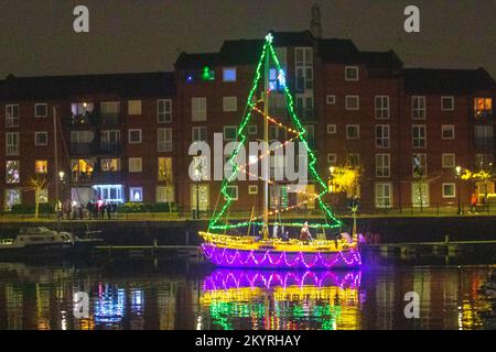 Lumières de Noël en mer. Une brillante parade de bateaux de vacances à Preston, Lancashire décembre 2022. Yachta et voiliers amarrés décorés de lumières de Noël étincelantes à Preston Marinaa. Une soirée de Noël s'allume pour les foules qui bordent le mur du quai tandis que les porte-couchettes illuminent leurs bateaux et profitent d'une voile en soirée sous les lumières festives. Banque D'Images