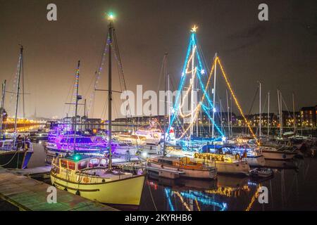 Lumières de Noël en mer. Une brillante parade de bateaux de vacances à Preston, Lancashire décembre 2022. Yachts amarrés et voiliers décorés de lumières de Noël étincelantes à Preston Marina. Une soirée de Noël s'allume pour les foules qui bordent le mur du quai tandis que les porte-couchettes illuminent leurs bateaux et profitent d'une voile en soirée sous les lumières festives. Banque D'Images