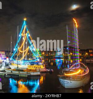 Lumières de Noël en mer. Une brillante parade de bateaux de vacances à Preston, Lancashire décembre 2022. Yachta et voiliers amarrés décorés de lumières de Noël étincelantes à Preston Marinaa. Une soirée de Noël s'allume pour les foules qui bordent le mur du quai tandis que les porte-couchettes illuminent leurs bateaux et profitent d'une voile en soirée sous les lumières festives. Banque D'Images