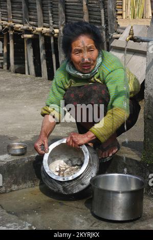 Ziro, Arunachal Pradesh, Inde - 03 04 2014 : Portrait de la femme tribale d'Apatani avec des tatouages traditionnels du visage et des bouchons de nez lave les pots de cuisine Banque D'Images