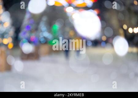 Arrière-plan flou. Rue de la ville pendant les chutes de neige en hiver. Beaucoup d'arbres de Noël décorés, éclairage, décoration sur la rue. Fête de Noël du nouvel an. Lanternes sur les arbres Banque D'Images