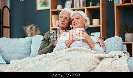 Détendez-vous, aimez et prenez un café avec un vieux couple sur un canapé avec une couverture pour se détendre, s'affectuer ou regarder la télévision. Confortable, confortable et retraite avec homme et Banque D'Images