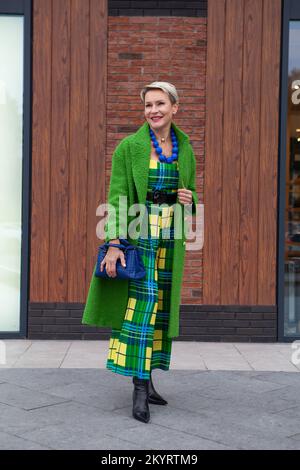 Portrait complet de femme âgée tendance, long manteau vert et élégante robe. Tendance de la mode pour l'automne ou le printemps. Ensemble femme élégant bleu Banque D'Images