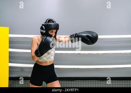 Une jeune femme lance un coup de poing dans un ring de boxe Banque D'Images