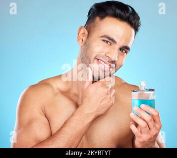 Beauté, cosmétiques et homme avec cologne en studio sur fond bleu pour le bien-être, l'auto-soin et le luxe. Soins de la peau, toilettage et modèle indien avec Banque D'Images