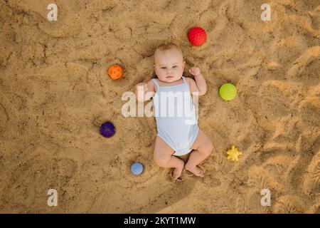 Vue de dessus d'un petit garçon heureux allongé sur une plage de sable Banque D'Images