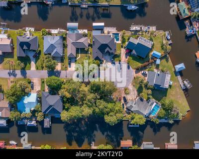 Vue aérienne des maisons en bord de mer le long d'une baie dans la communauté de Navarre en Floride. Maisons résidentielles et maisons en rangée vues d'en haut avec de petits bateaux ancrés à Banque D'Images