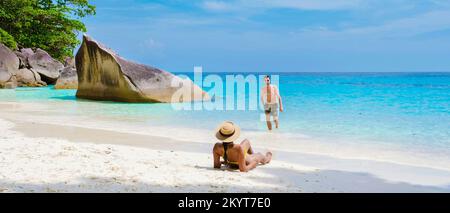 Un couple d'hommes et de femmes se détendant au soleil sur la plage tropicale blanche avec la tourte de couleur océan des îles Similan en Thaïlande. Banque D'Images