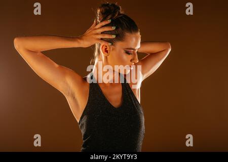 Un magnifique modèle féminin posé sur un fond orange. La mode en studio Banque D'Images