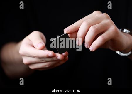 Mains Mans tenant une petite boîte noire carrée avec une copie vide espace pour le texte et le design isolé sur fond sombre. Carte, vierge, modèle, maquette, Banque D'Images