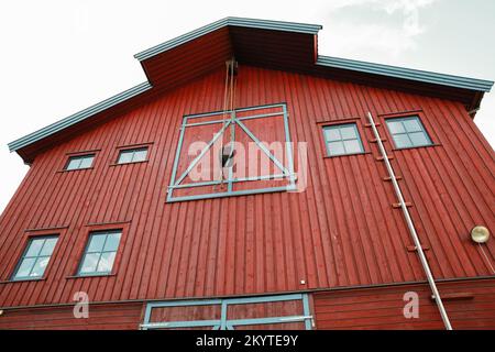 Façade de grange en bois rouge avec grue à poutre manuelle. Bâtiment portuaire d'époque. Norvège Banque D'Images