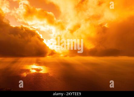 Vue aérienne coucher de soleil rouge sur la mer avec falaise volcanique rocheuse. Résumé nature été coucher de soleil océan mer fond. Petites vagues sur doré chaud Banque D'Images