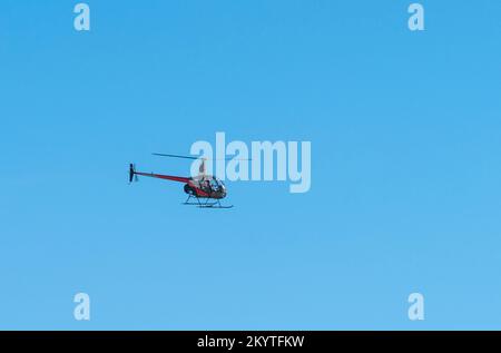 Petit hélicoptère volant dans une ambiance ensoleillée devant le ciel bleu Banque D'Images