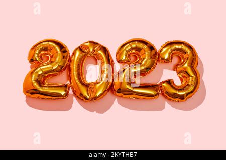 quelques ballons dorés en forme de nombre formant le numéro 2023, comme la nouvelle année, sur un fond rose Banque D'Images