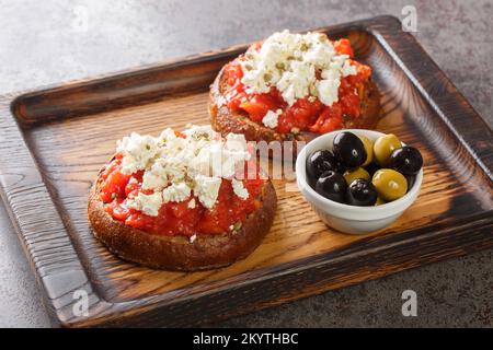 Dakos se compose d'une tranche de pain d'orge craqué et garni de tomates mûres écrasées ou râpées et de feta émietté avec origan et olives closeup o Banque D'Images