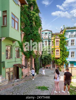 Istanbul, Turquie - 28 août 2022: Touristes prenant des photos commémoratives en face de vieilles maisons colorées traditionnelles dans le vieux quartier de Balat, en une journée d'été Banque D'Images
