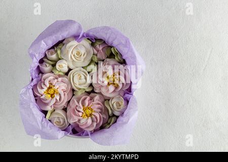 Guimauves faites maison dans une boîte cadeau. Fleurs de guimauve sur fond gris Banque D'Images