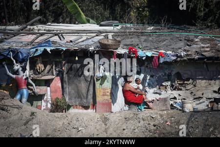 Katmandou, Bagmati, Népal. 2nd décembre 2022. Une femme avec son bébé se couche le soleil à l'extérieur de sa hutte dans un bidonville sur la rive de la rivière Bagmati, dans la région de Thapathali à Katmandou, au Népal, sur 2 décembre 2022. Les autorités ont ordonné la suppression de la colonie de taudis résidant dans diverses parties de la ville. (Image de crédit : © Sunil Sharma/ZUMA Press Wire) Banque D'Images