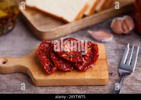 Tomates séchées à l'huile d'olive sur une mini-pension avec du pain maison dans un style rustique. Cuisine traditionnelle maison. Mise au point sélective, gros plan. Banque D'Images