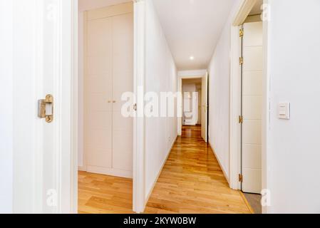 Couloir de distribution de logements avec parquet en chêne français et portes, armoires et plinthes laquées blanches Banque D'Images