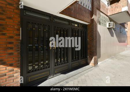 Porte en métal à la rue poignées peintes en noir et or dans un bâtiment de logement unifamilial Banque D'Images