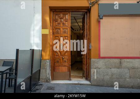 Petite porte lambrissée de bois donnant sur la rue avec des knockers et des poignées en laiton dans un ancien immeuble d'appartements Banque D'Images