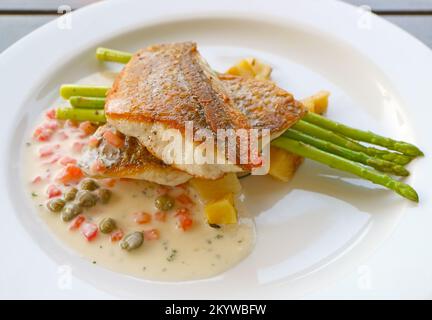 Assiette de délicieux bar de mer poêlé avec sauce à la crème de moutarde à la caper de tomate Banque D'Images
