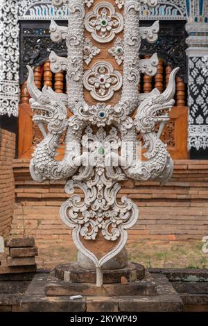 Stuc blanc sur brique bannière religieuse traditionnelle de style Lanna avec naga au temple historique Wat Lok Moli ou Lok Molee bouddhiste, Chiang Mai, Thaïlande Banque D'Images