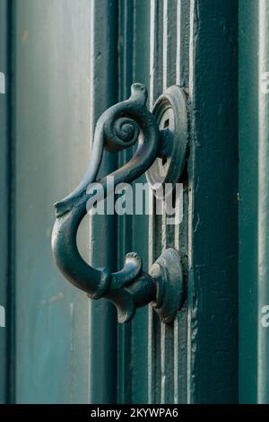 Vue rapprochée d'une poignée de porte en laiton d'époque en forme de tête d'oiseau stylisée isolée sur une ancienne porte en bois vert, Montpellier, France Banque D'Images