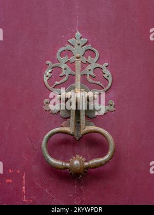 Vue rapprochée d'un magnifique knocker de porte en laiton d'époque isolé sur une ancienne porte en bois rouge framboise, Montpellier, France Banque D'Images