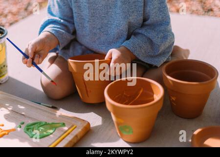 Petite fille peinture pots de fleurs dehors au soleil à Saint Geo Banque D'Images