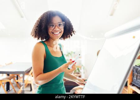 Belle fille afro-américaine aux cheveux fclés foncés debout près du bord et donnant la présentation à des collègues au bureau. Jeune femme d'affaires à la recherche Banque D'Images