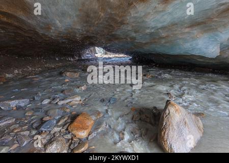 Entrée de la grotte de glace sculptée dans le glacier de Vallelunga traversé par un ruisseau Banque D'Images