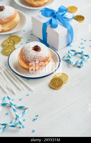 Bonne Hanoukkah. Beignets sucrés Hanukkah, boîtes-cadeaux, bougies blanches et pièces de chocolat sur fond de bois blanc. Image et concept d'holida juif Banque D'Images