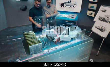Deux ingénieurs les développeurs qui se trouvent dans un studio de conception près d'une table holographique futuriste et font un test dans un simulateur d'essai de collision de voiture 3D, qui simule un accident de la route, vérifient la sécurité Banque D'Images