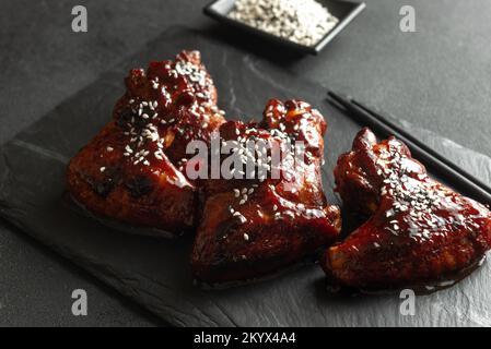 Ailes de poulet à la sauce teriyaki. Ailes de poulet asiatiques sur fond sombre Banque D'Images