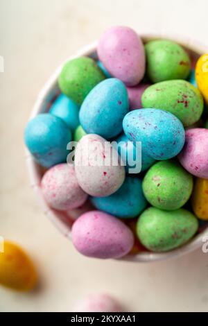 Gros plan sur un tas d'œufs de pâques au chocolat colorés tirés d'en haut Banque D'Images