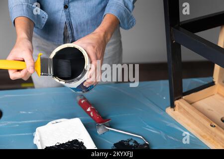 Les jeunes femmes se préparant à restaurer un escabeau pour les enfants comme une amélioration de maison de passe-temps. Sur une table couverte. Peindre avec un pinceau Banque D'Images