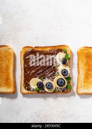 Grenaille supérieure d'un pain de blé avec tartiner au chocolat, tranches de banane et baies dessus Banque D'Images