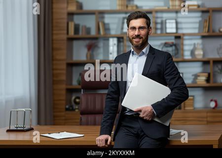 Portrait d'un professeur d'université mature, homme en costume d'affaires et bureau du directeur de l'académie regardant l'appareil photo et souriant. Banque D'Images