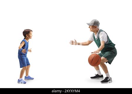 Photo pleine longueur d'un enfant jouant au basket-ball avec un homme âgé isolé sur fond blanc Banque D'Images